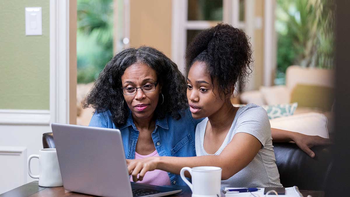 parent and student sit in front of a laptop researching.